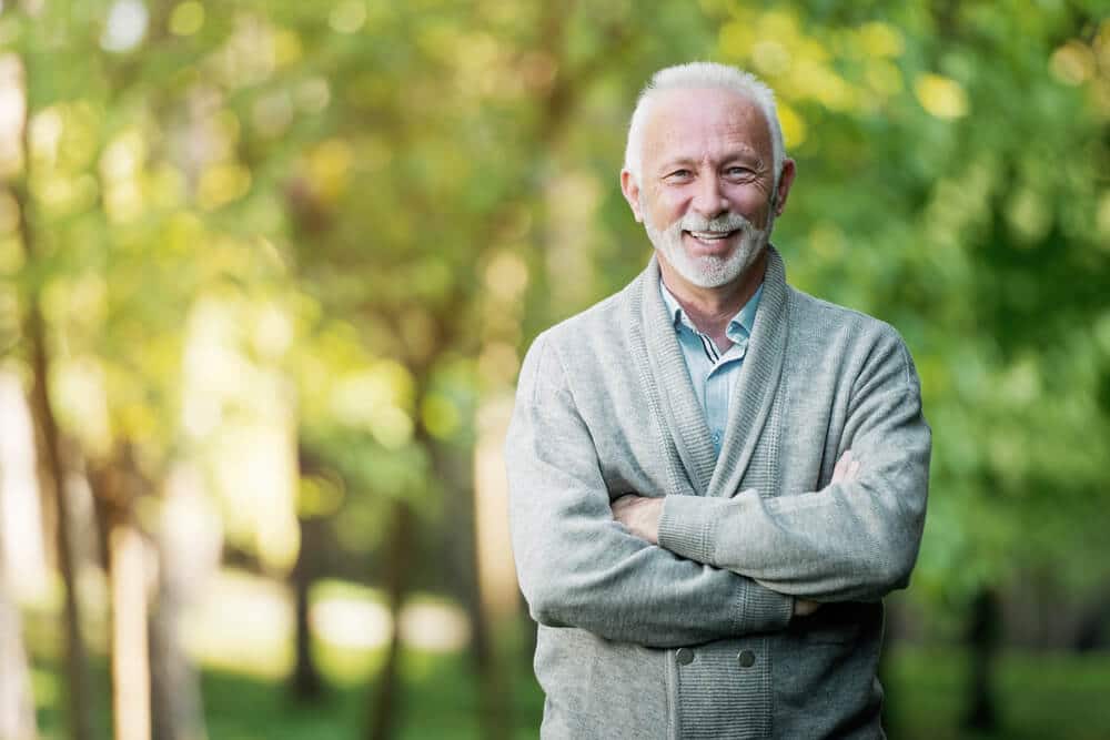 Smiling older man outside with trees in the background