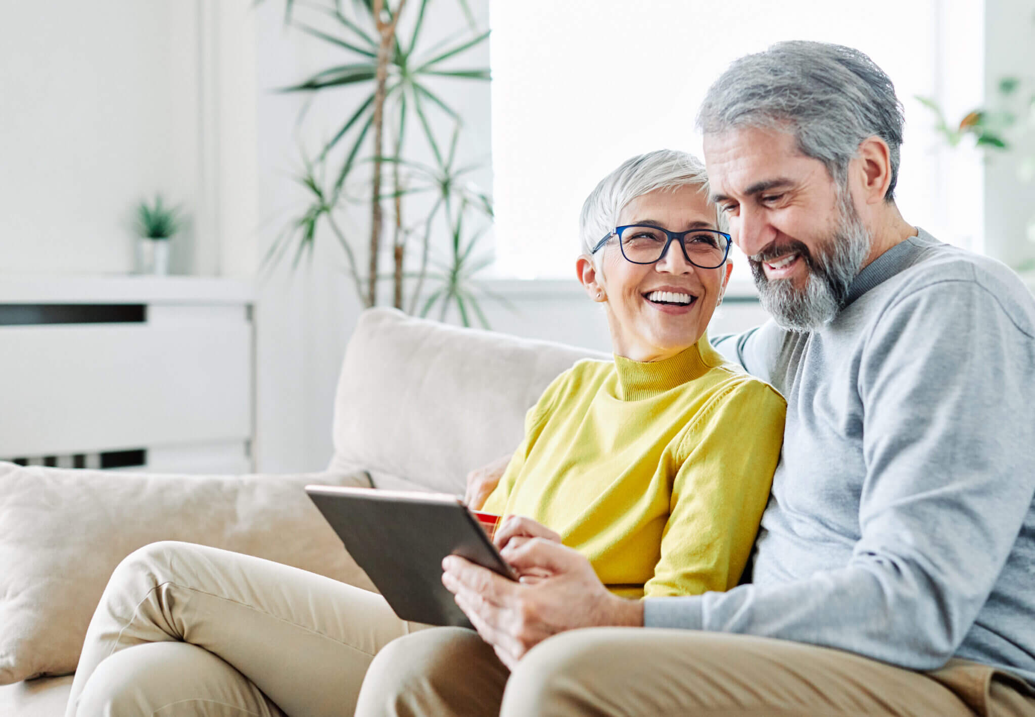 portrait of happy smiling senior couple using tablet at home